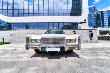 Classic american retro beige muscle car. Old rare cars in modern city