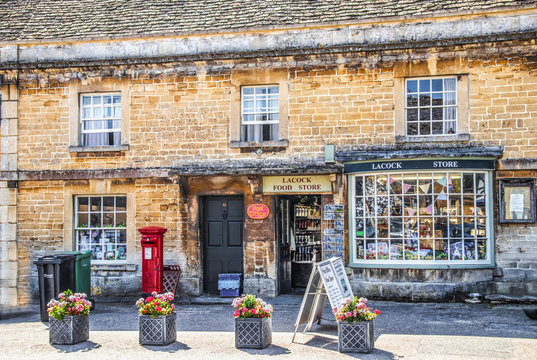 7-25-2019 Lacock UK - Village Store And Post Office Open On Sunny Day In LaCock UK With Flowers Out Front Of Ancient Buildings With Postcards On Rack