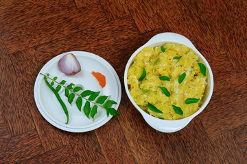 Tasty south indian kappa puzhukku, cooked tapioca in a white bowl isolated on wooden background