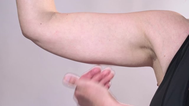 Middle-aged woman holding a hand with excess fat. On a white background, Isolated.