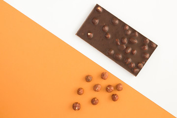 Dark chocolate with hazelnuts on the two-color background. Top view. Copy space.