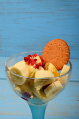 ice cream dessert with banana pieces and frozen raspberries and chocolate cake on a blue background