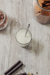 Chocolate waffles, cocoa powder, a jar of cookies and a glass of milk on a rustic wooden background, as a breakfast or sweet dessert, selective focus