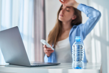 Upset tired working woman suffering from heat and hot weather during online work at computer at...