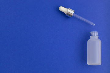 A bottle for collagen moisturizing hyaluron serum on indigo background. Colour of the year 2020.