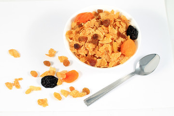 close up of muesli with dried fruits and yogurt in bowl on white background
