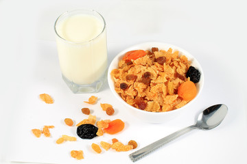 close up of muesli with dried fruits and yogurt in bowl on white background