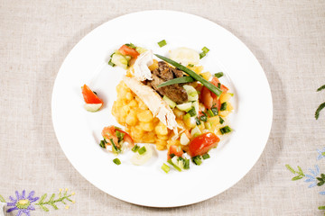 close up of potato with chicken with vegetables and salad on plate