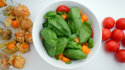 Culinary travel. Vegetarian.  Health & vegetarian concept.
Salad with sesam, cherry tomatoes and basil on plate on white table. Top view.