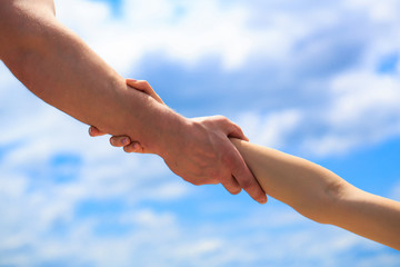 Giving a helping hand. Hands of man and woman on blue sky background. Lending a helping hand. Hands...
