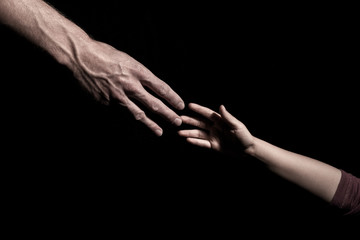 Fototapeta na wymiar Hands reaching out to each other on dark black background