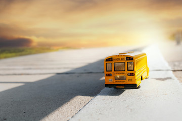 Fototapeta na wymiar Yellow school bus toy model on country road.