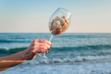 Glass with shells on a background of the sea