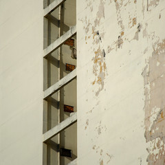 close up on a beige facade with a few windows and peeled paint