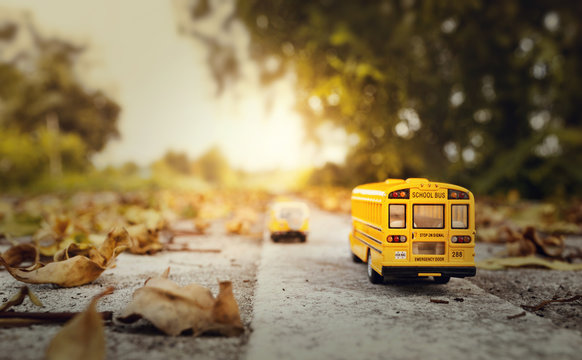 Yellow school bus toy model on country road.