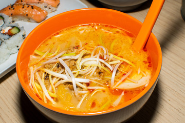 Asian noodle soup, ramen with chicken, tofu, vegetables and egg in black bowl. Slate background