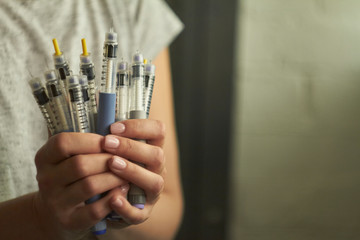 Diabetes insulin dependent concept, hands with syringes pen injectors with doses of humalog for subcutaneous abdomen injection therapy