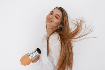 Beautiful teenage girl blowing her hair with hairdryer. Beauty and hait concept.