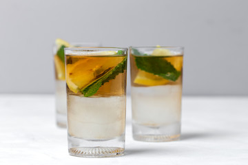 tea with ice, mint and lemon wedges on white table