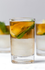 tea with ice, mint and lemon wedges on white table