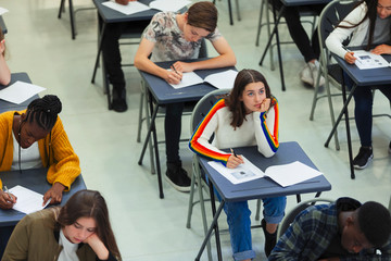 Thoughtful high school girl taking exam at desk in classroom