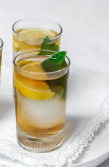 tea with ice, mint and lemon wedges on white table