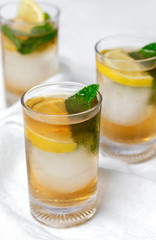 tea with ice, mint and lemon wedges on white table