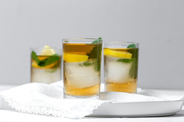 Fototapeta na wymiar tea with ice, mint and lemon wedges on white table