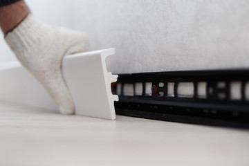 Man putting new skirting board on wall in house