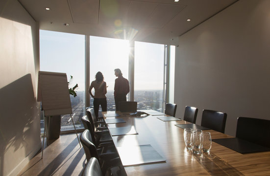 Business people talking at sunny highrise conference room window
