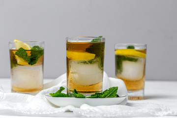 tea with ice, mint and lemon wedges on white table
