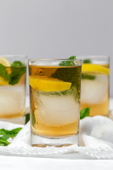 tea with ice, mint and lemon wedges on white table