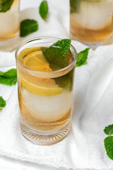 tea with ice, mint and lemon wedges on white table
