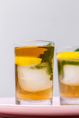 tea with ice, mint and lemon wedges on white table