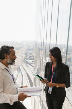 Business people discussing paperwork in highrise office window