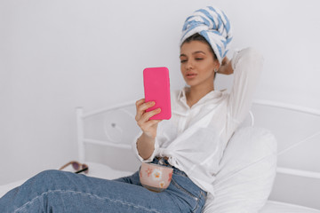 Cute pretty girl is wearing towel on her head taking pictures with phone. Beauty and stay home concept.