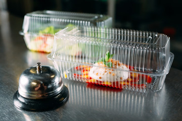 food delivery. distribution table in a restaurant with a metal bell. food in plastic containers....