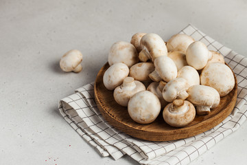  Fresh champignon porcini mushrooms on a wooden plate. Food for vegetarians. Copy space