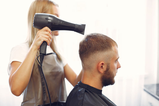 Man with a beard. Hairdresser with a client. Woman drying man's hair