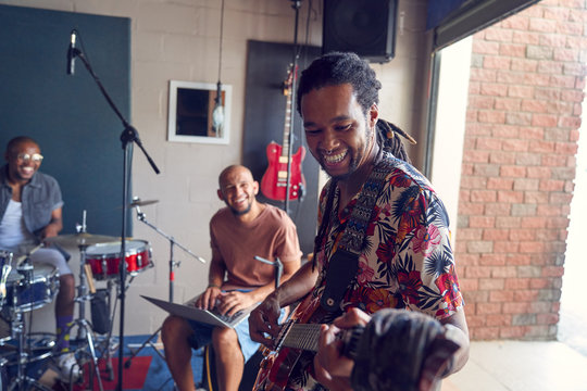 Smiling male musicians practicing in garage recording studio