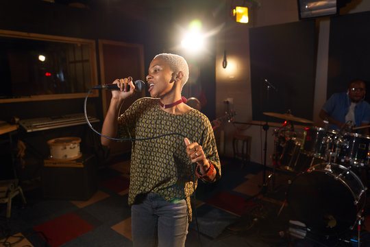 Female musician singing into microphone in recording studio