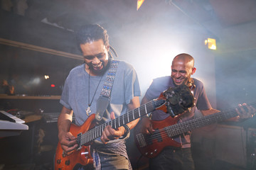 Happy male musicians playing electric guitar in recording studio