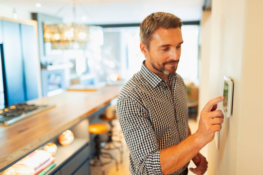 Man Adjusting Digital Home Automation Thermostat