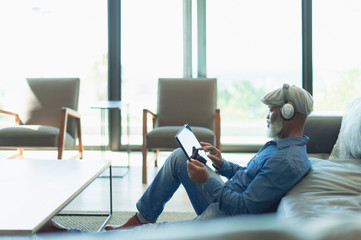 Man relaxing, listening to music with headphones and digital tablet in living room
