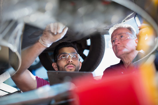 Male mechanics working under car in auto repair shop