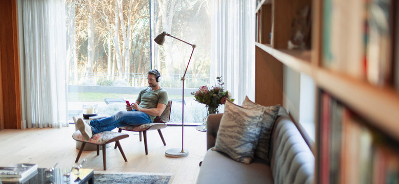Man relaxing, listening to music with headphones and mp3 player in living room