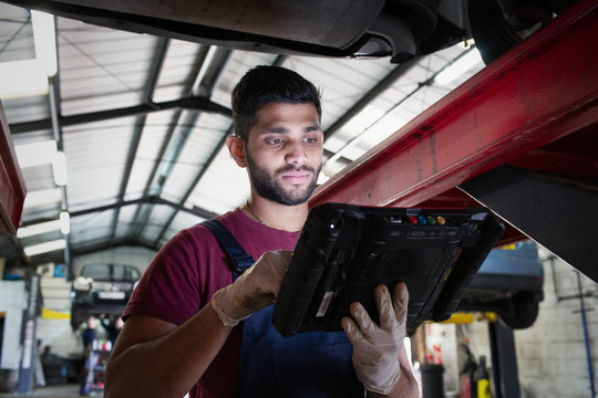 Focused male mechanic using diagnostic equipment in auto repair shop