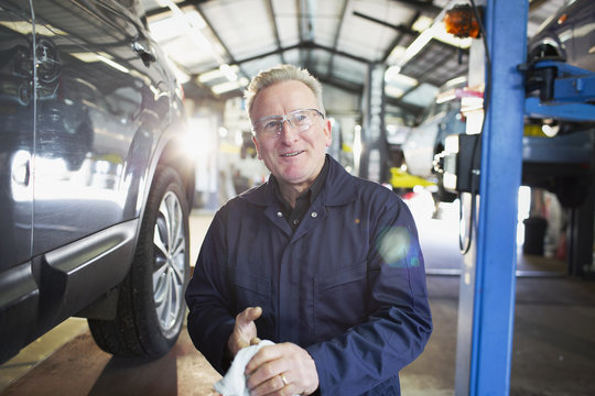 Portrait confident male mechanic wiping hands in auto repair shop