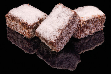 Tasty pieces of chocolate brownie with reflection, isolated on black background.