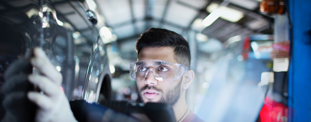 Focused male mechanic examining car in auto repair shop